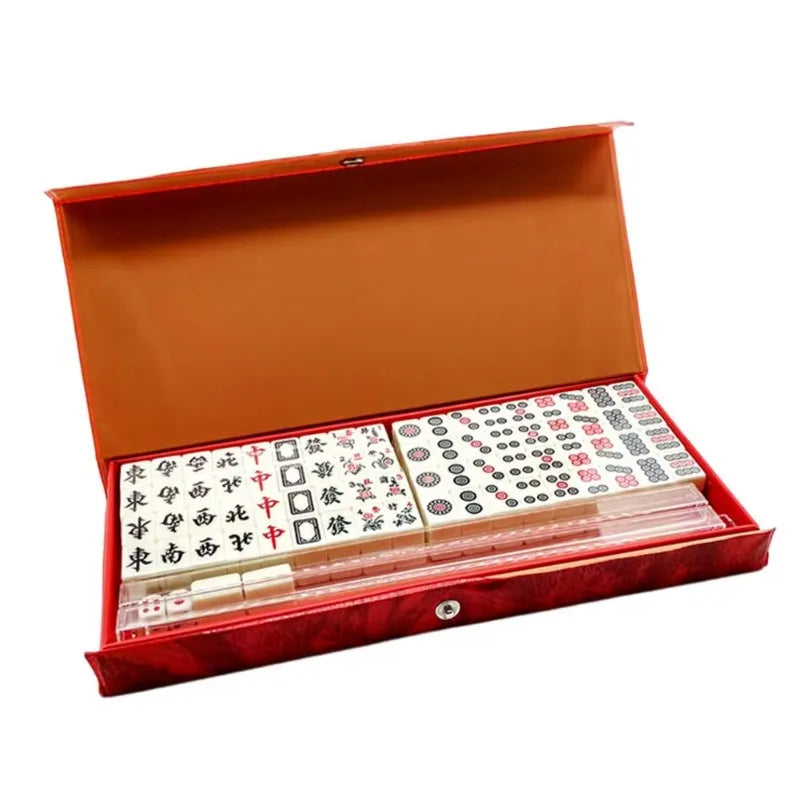 Travel size mahjong set in a long red case, open on two blocks of tiles, clear racks, dice and spare tiles