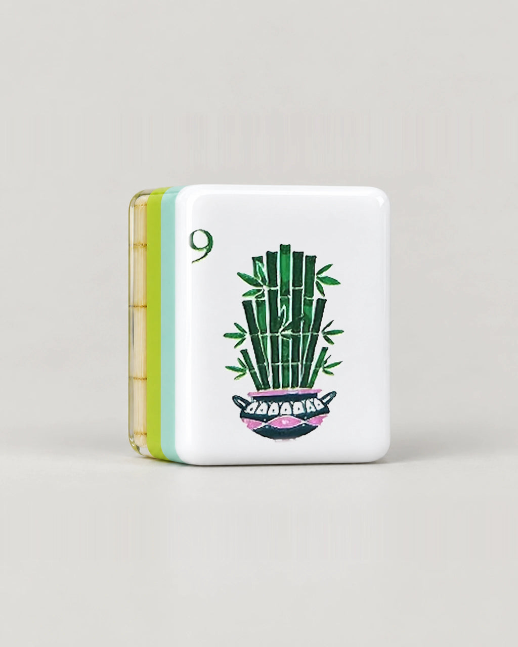 Close-up of one Monstera bamboo mahjong tile, the 9 Bam with potted bamboo, showing its white face and the mint, lime green and clear bamboo layers along its edge