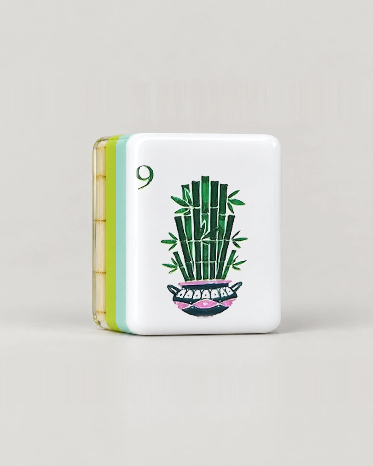 Close-up of one Monstera bamboo mahjong tile, the 9 Bam with potted bamboo, showing its white face and the mint, lime green and clear bamboo layers along its edge