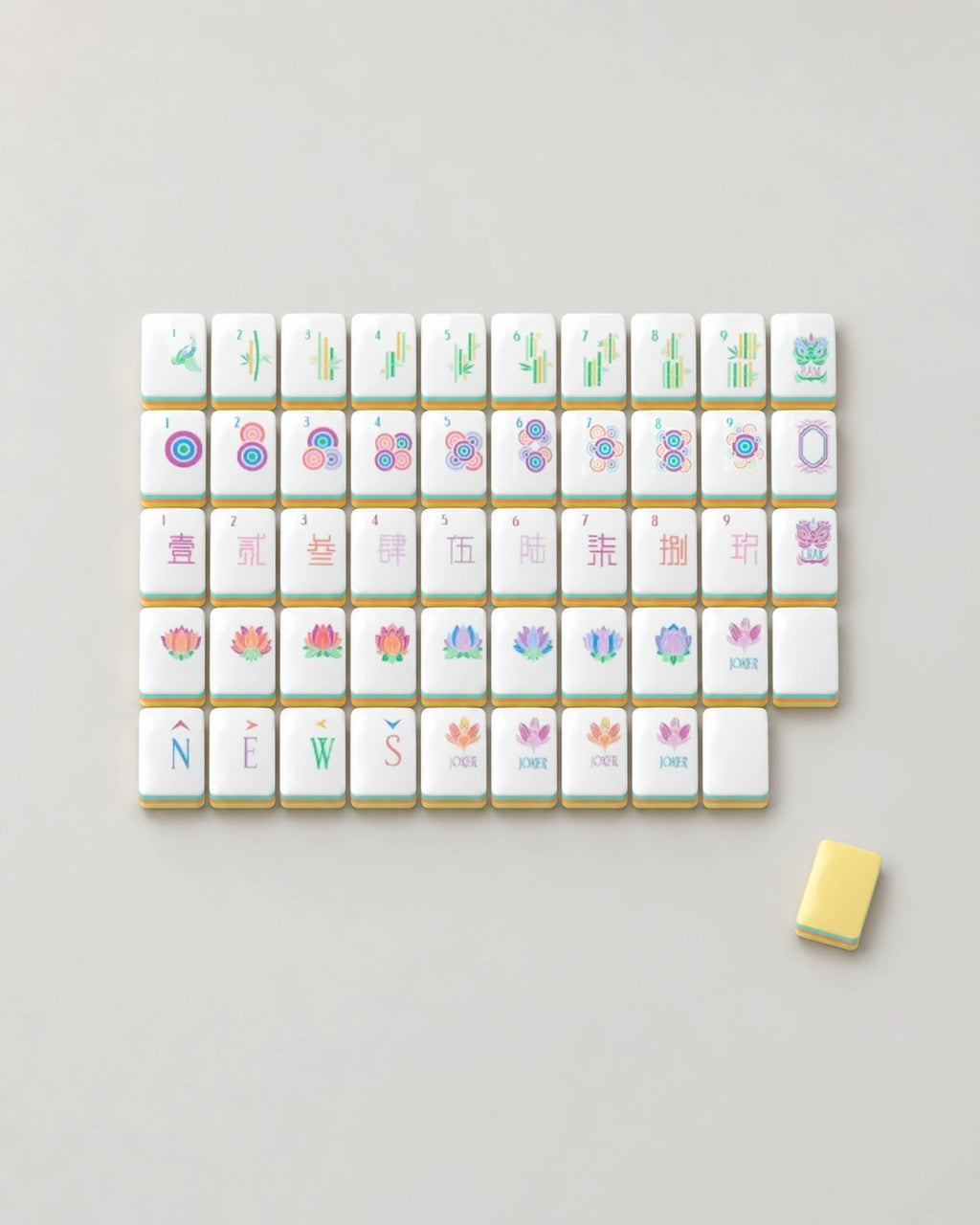 Sherbet pastel mahjong tiles laid out face up, showing every dot, bam, crak, wind, dragon and lotus flower, both lotus-bud joker colorways and a blank, beside one butter yellow tile back